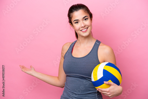Young Brazilian woman playing volleyball isolated on pink background extending hands to the side for inviting to come