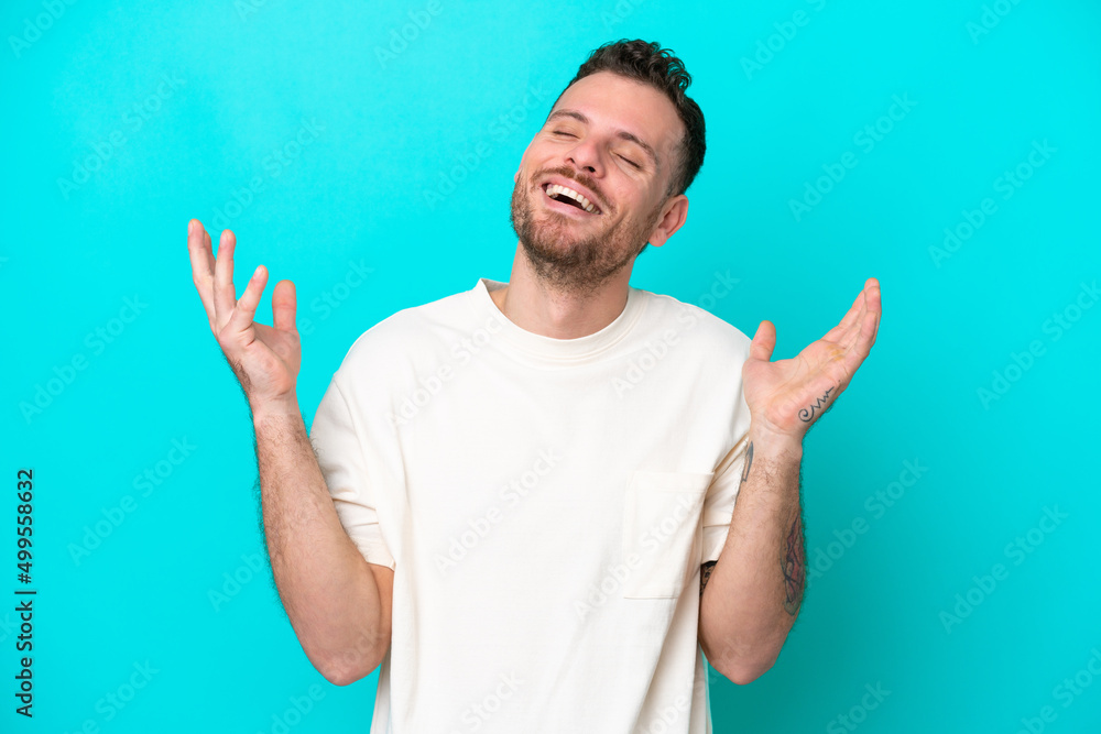 Naklejka premium Young Brazilian man isolated on blue background smiling a lot