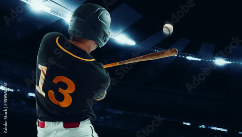 Photography Back view of professional baseball player with baseball bat in action during match at stadium at evening time
