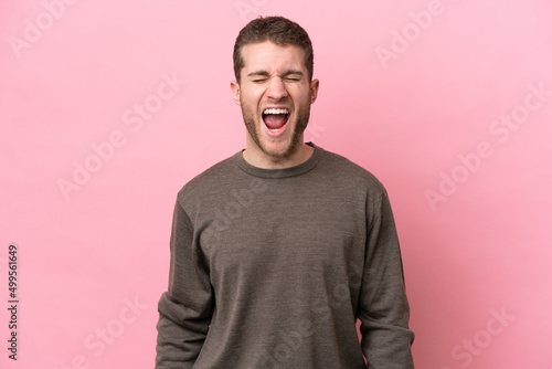 Young caucasian man isolated on pink background shouting to the front with mouth wide open