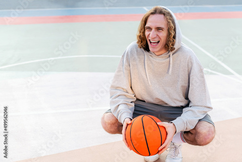 man laughing as he rests after playing basketball