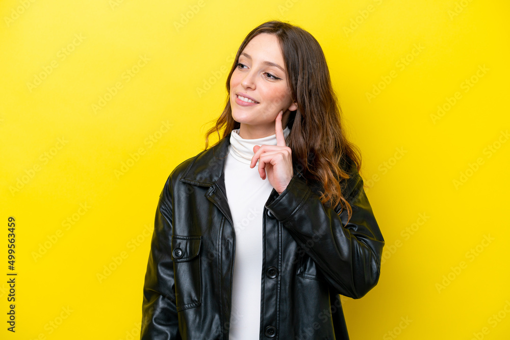 Young caucasian woman isolated on yellow background thinking an idea while looking up