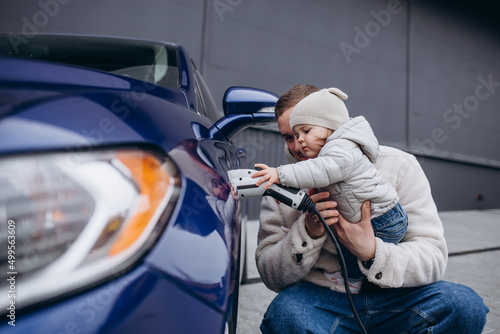Quadro em tela father playing with daughter while charging electric car