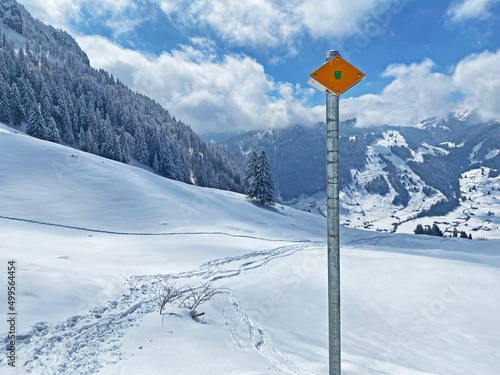 Hiking markings and orientation signs with signposts for navigating in the idyllic winter ambience on the Alpstein mountain massif and in the Swiss Alps - Nesslau, Switzerland / Schweiz