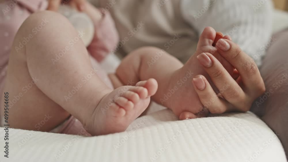 Selective focus of cropped mother holding foot of her baby girl at home in afternoon Selective focus of cropped mother holding foot of her baby girl at home in afternoon
