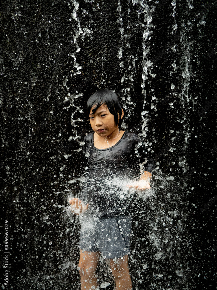 Fototapeta premium Young asian boy have fun with small waterfall