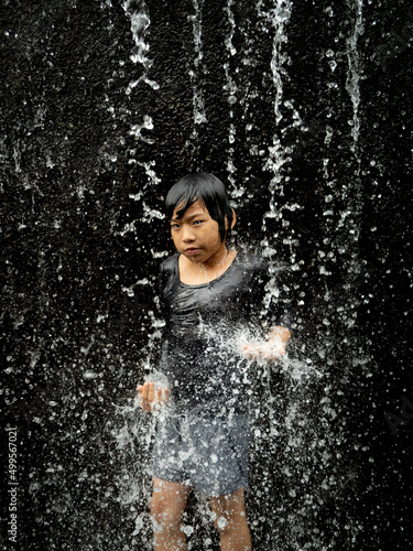 Young asian boy have fun with small waterfall