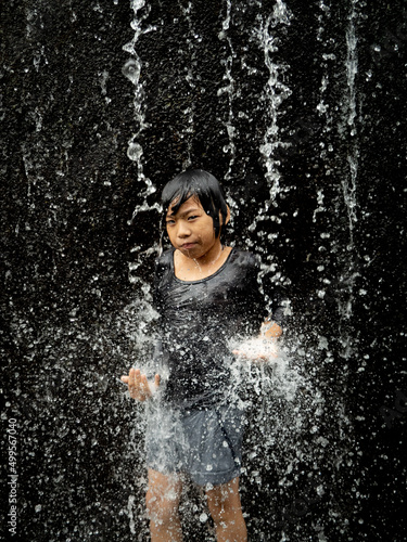 Young asian boy have fun with small waterfall