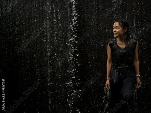 Young asian woman have fun with small waterfall  