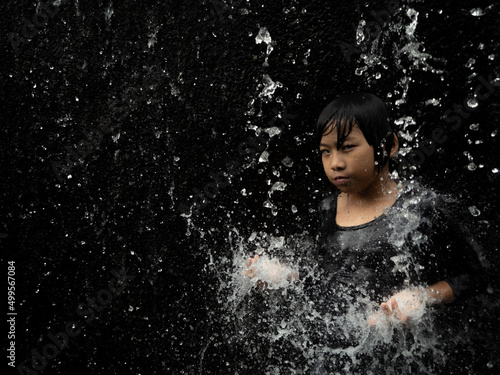 Young asian boy have fun with small waterfall