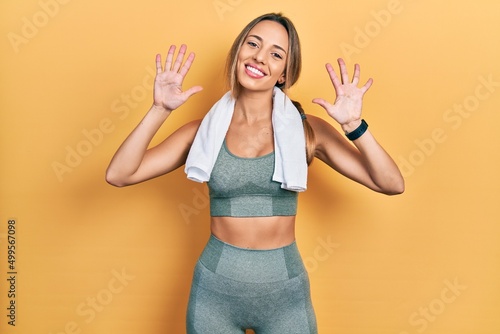 Beautiful hispanic woman wearing sportswear and towel showing and pointing up with fingers number ten while smiling confident and happy. © Krakenimages.com