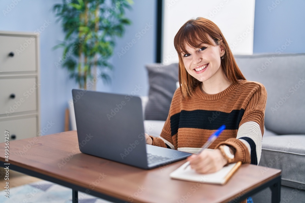 Young woman using laptop writing on notebook at home Young woman using laptop writing on notebook at home