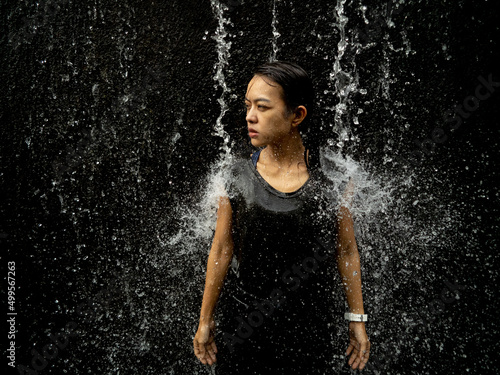 Young asian woman have fun with small waterfall  