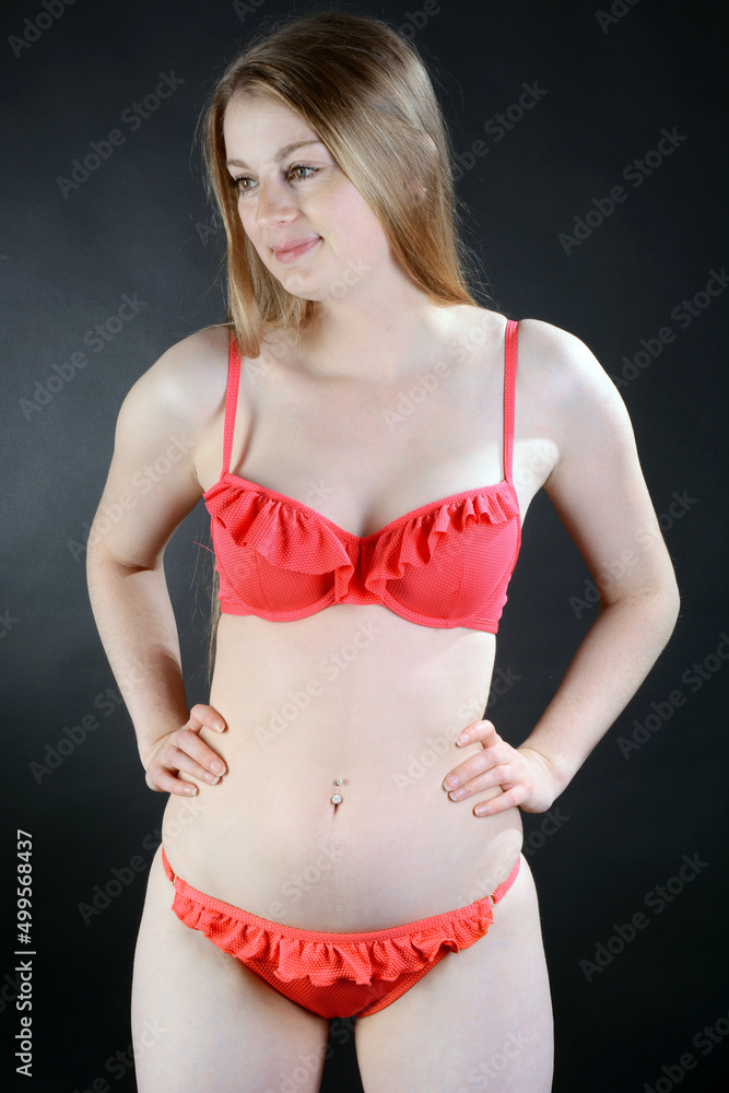 Gorgeous young woman posing in red bikini in studio