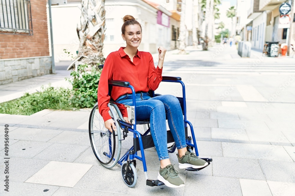 Young brunette woman sitting on wheelchair outdoors screaming proud, celebrating victory and success very excited with raised arms Young brunette woman sitting on wheelchair outdoors screaming proud, celebrating victory and success very excited with raised arms