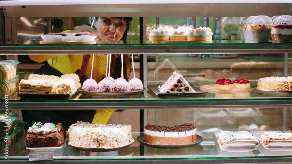 Concept of small business and entrepreneur smiling large saleswoman take some deserts from the showcase fridge to selling them Concept of small business and entrepreneur smiling large saleswoman take some deserts from the showcase fridge to selling them