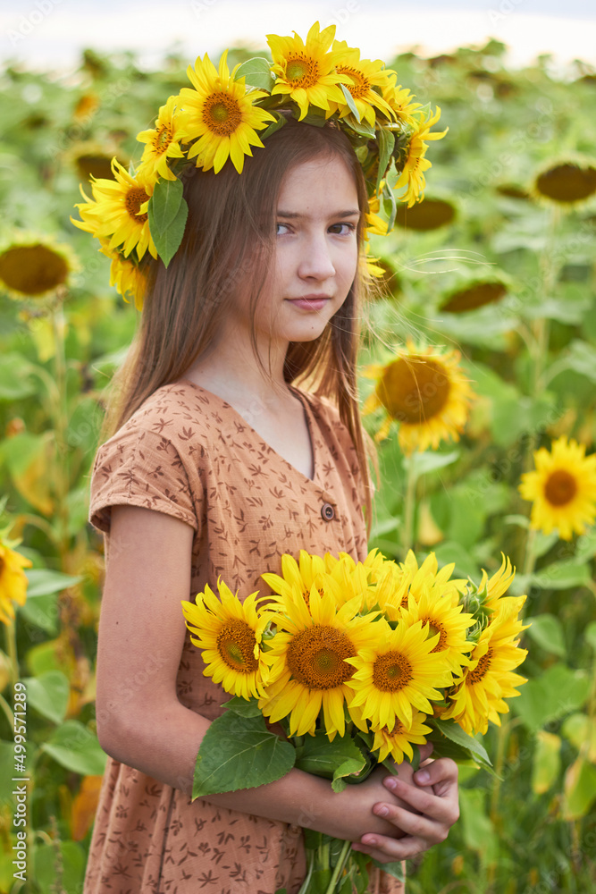 Little beautiful girl in the field
with a wreath of sunflowers on his head with a bouquet in his hands. Little beautiful girl in the field
with a wreath of sunflowers on his head with a bouquet in his hands.