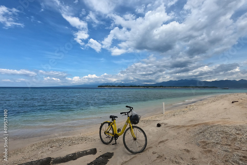 Yellow bicycle parking at the sandy beach under dramatic blue sky, sea side. 