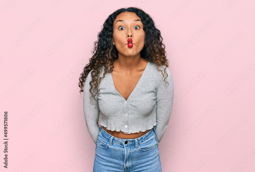 Young hispanic woman with curly hair wearing casual clothes making fish face with lips, crazy and comical gesture. funny expression. Young hispanic woman with curly hair wearing casual clothes making fish face with lips, crazy and comical gesture. funny expression.