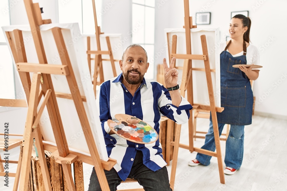 Senior artist man at art studio smiling with happy face winking at the camera doing victory sign with fingers. number two. Senior artist man at art studio smiling with happy face winking at the camera doing victory sign with fingers. number two.