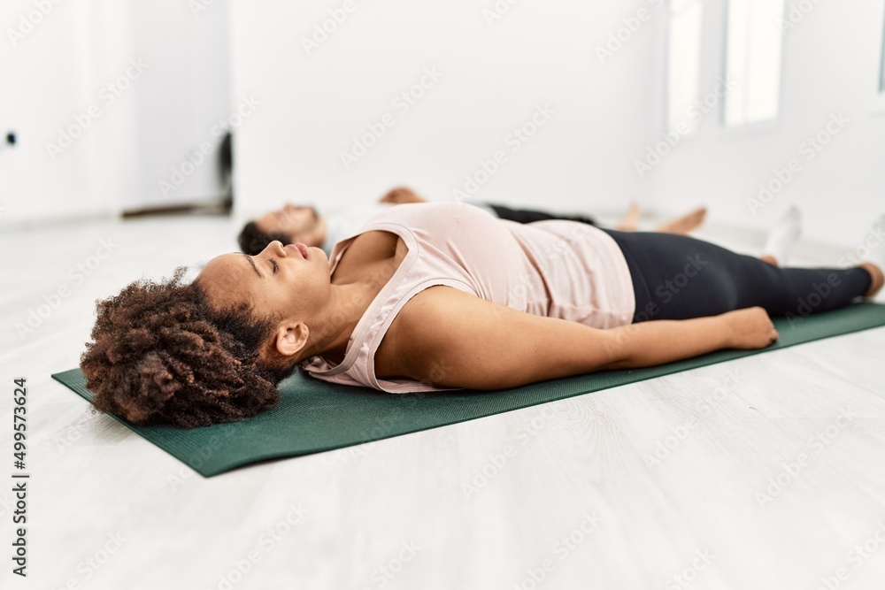 Young african american woman and hispanic man exercising at pilates room, stretching body and doing yoga pose, training strength and balance Young african american woman and hispanic man exercising at pilates room, stretching body and doing yoga pose, training strength and balance