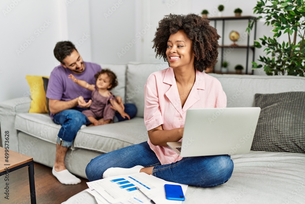 Mother of interracial family working using computer laptop at home looking away to side with smile on face, natural expression. laughing confident. Mother of interracial family working using computer laptop at home looking away to side with smile on face, natural expression. laughing confident.