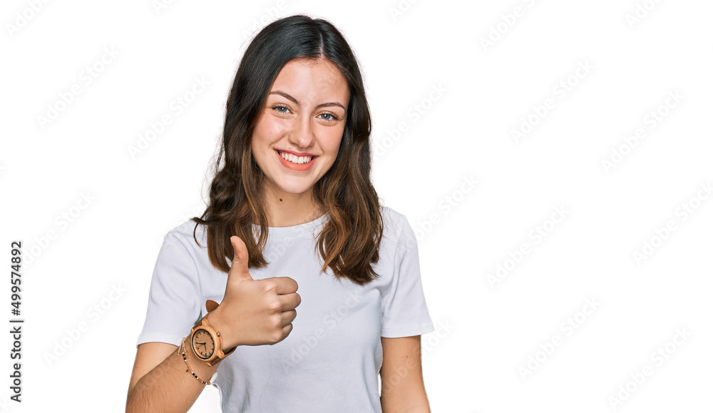 Young beautiful woman wearing casual white t shirt doing happy thumbs up gesture with hand. approving expression looking at the camera showing success. Young beautiful woman wearing casual white t shirt doing happy thumbs up gesture with hand. approving expression looking at the camera showing success.