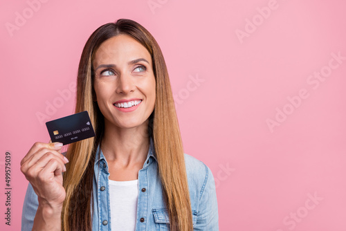 Photo of young cheerful woman interested hold bank card look empty space profit Fototapet