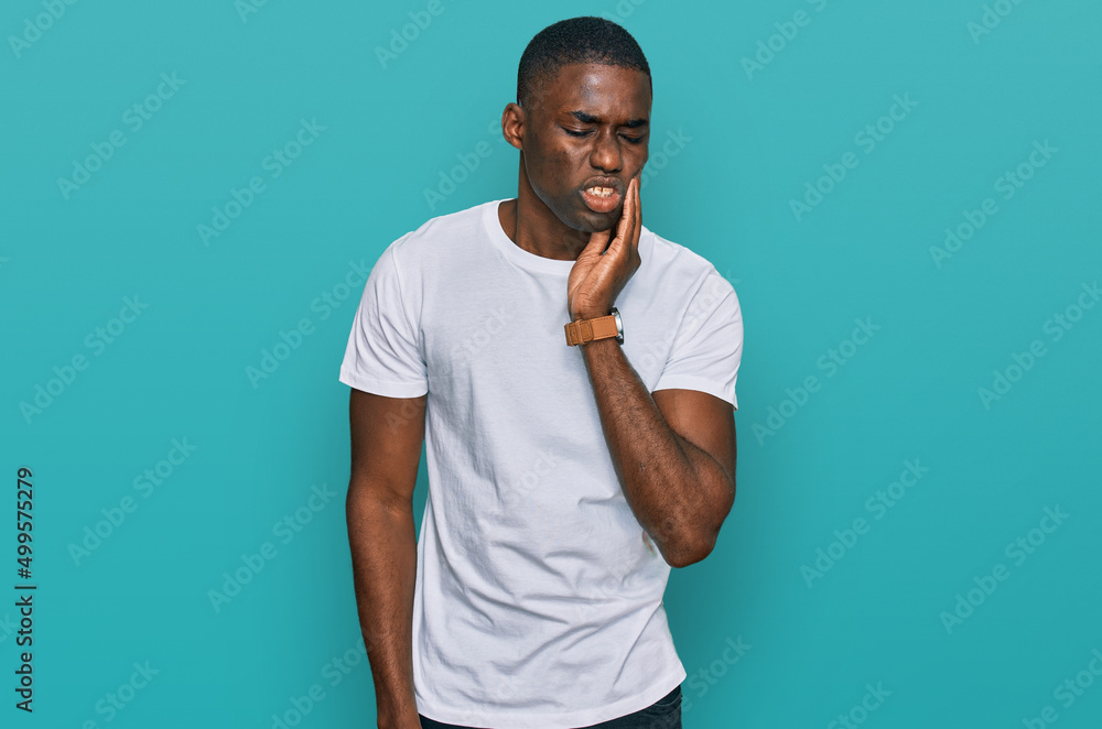 Young african american man wearing casual white t shirt touching mouth with hand with painful expression because of toothache or dental illness on teeth. dentist Young african american man wearing casual white t shirt touching mouth with hand with painful expression because of toothache or dental illness on teeth. dentist