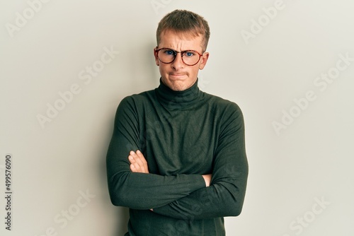 Young caucasian man wearing glasses with arms crossed gesture skeptic and nervous, frowning upset because of problem. negative person.