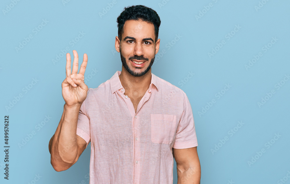 Fototapeta premium Hispanic man with beard wearing casual shirt showing and pointing up with fingers number three while smiling confident and happy.