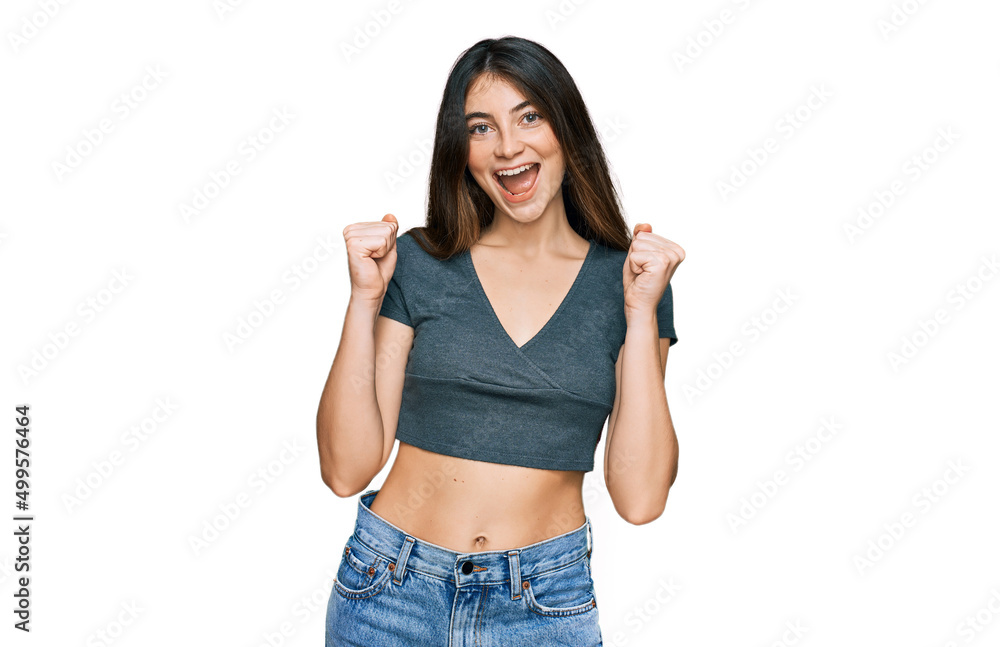 Young beautiful teen girl wearing casual crop top t shirt celebrating surprised and amazed for success with arms raised and open eyes. winner concept. Young beautiful teen girl wearing casual crop top t shirt celebrating surprised and amazed for success with arms raised and open eyes. winner concept.