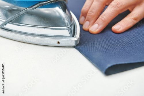 Tailor ironing foldes in fabric . Clothes sewing. Clothing repair. Tailoring. Close up view photo