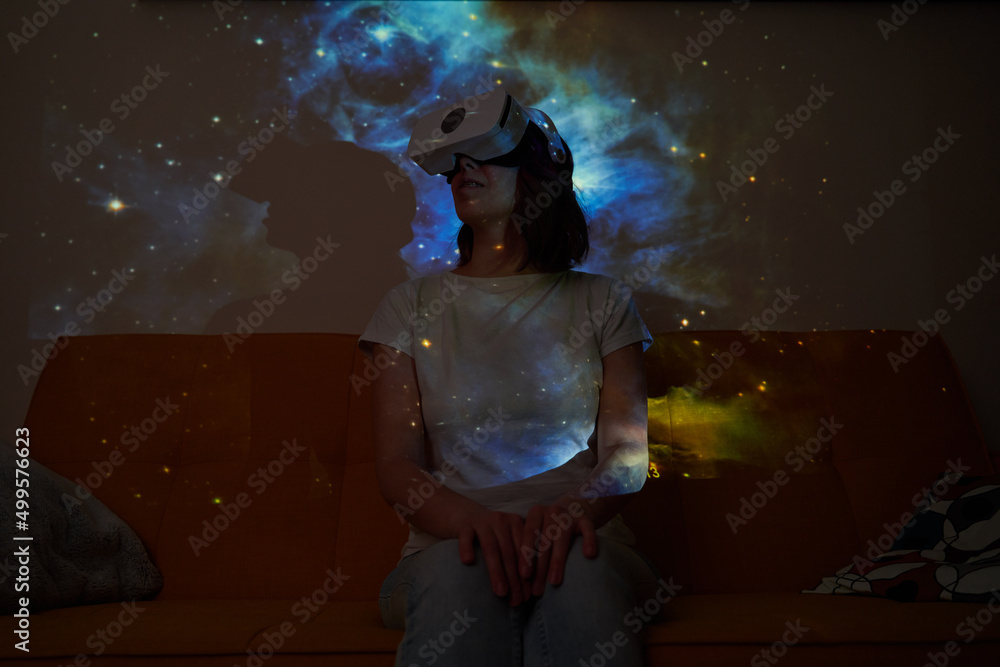 Woman uses virtual reality glasses to see the galaxy space. Elements of this image furnished by NASA.