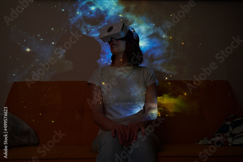 Woman uses virtual reality glasses to see the galaxy space. Elements of this image furnished by NASA.