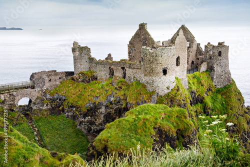 Ruins of Dunluce Castle, Antrim, Northern Ireland during sunny day with semi cloudy sky. Irish ancient castle near Wild Atlantic Way. photo