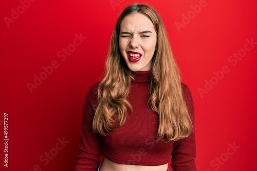 Young blonde woman wearing turtleneck sweater winking looking at the camera with sexy expression, cheerful and happy face.