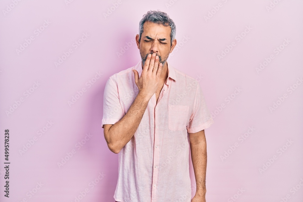 Handsome middle age man with grey hair wearing casual shirt bored yawning tired covering mouth with hand. restless and sleepiness. Handsome middle age man with grey hair wearing casual shirt bored yawning tired covering mouth with hand. restless and sleepiness.