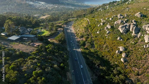 Cars Driving Through Highway In The Mountains in Llandudno overlooking Houtbay in Cape Town, South Africa - aerial shot