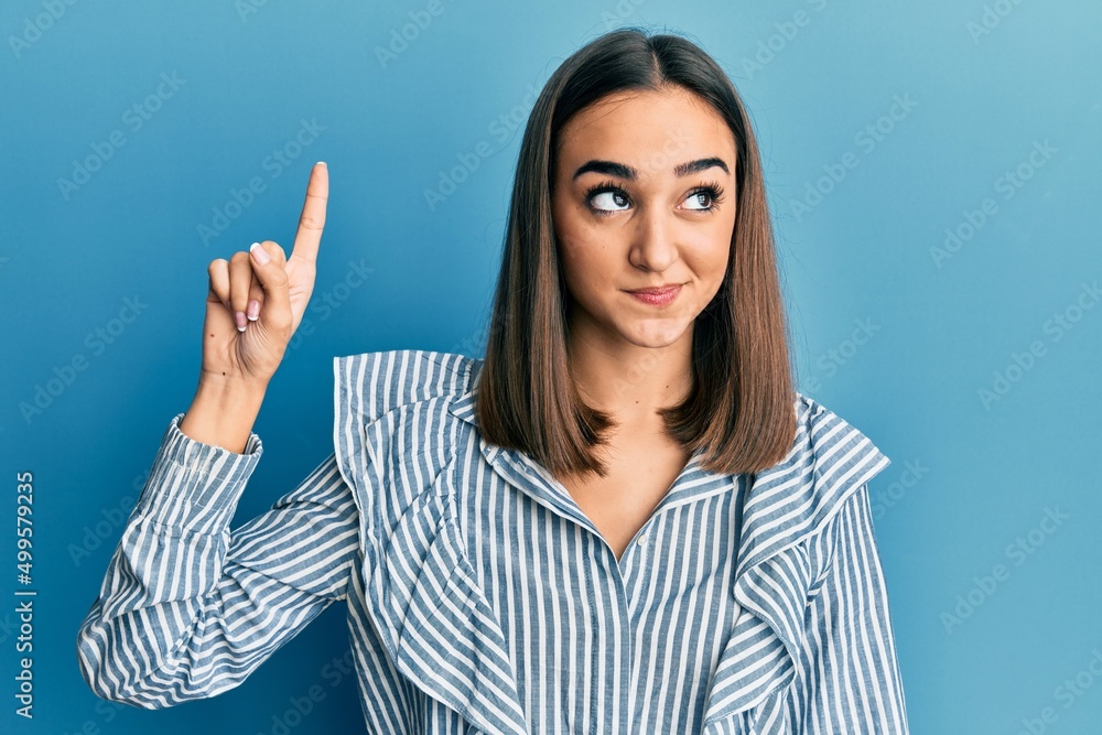 Young brunette student girl pointing up with finger smiling looking to the side and staring away thinking. Young brunette student girl pointing up with finger smiling looking to the side and staring away thinking.