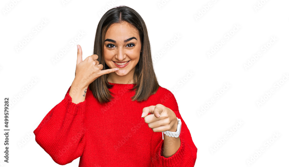 Beautiful brunette woman wearing casual winter sweater smiling doing talking on the telephone gesture and pointing to you. call me. Beautiful brunette woman wearing casual winter sweater smiling doing talking on the telephone gesture and pointing to you. call me.