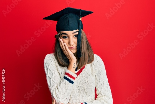 Young brunette girl wearing graduation cap thinking looking tired and bored with depression problems with crossed arms.