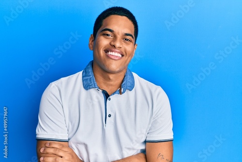 Young handsome hispanic man wearing casual clothes happy face smiling with crossed arms looking at the camera. positive person.