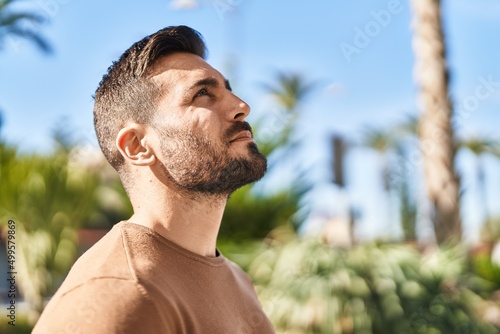 Young hispanic man with relaxed expression looking to the sky at park