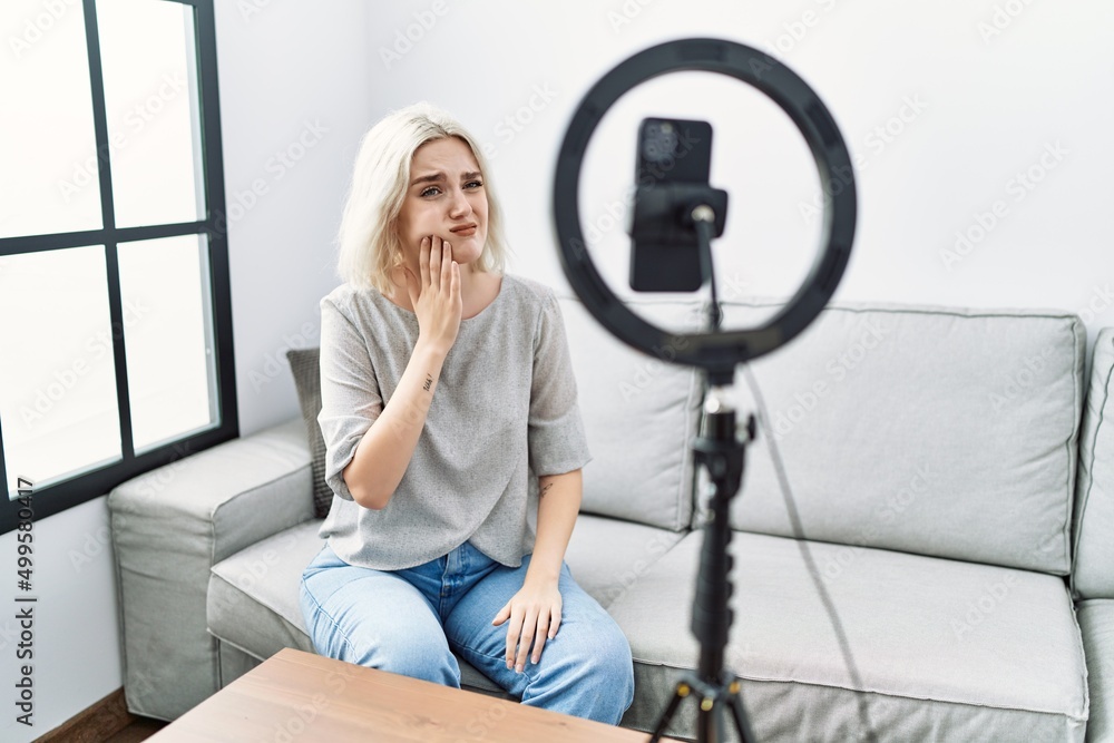 Φωτογραφία Young caucasian woman recording vlog tutorial with smartphone at home touching mouth with hand with painful expression because of toothache or dental illness on teeth