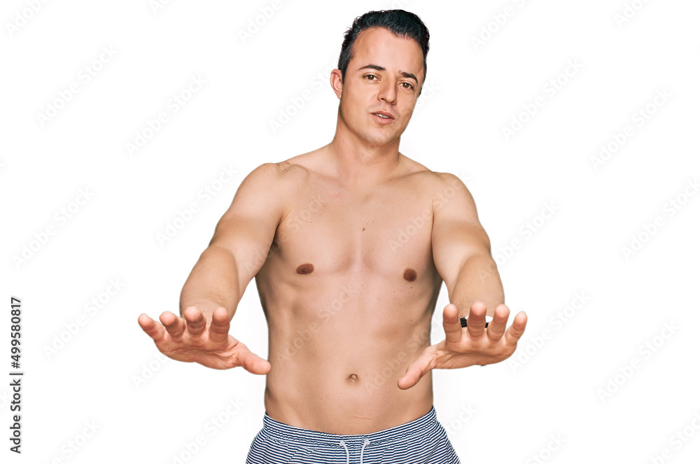 Handsome young man wearing swimwear shirtless doing stop gesture with hands palms, angry and frustration expression Handsome young man wearing swimwear shirtless doing stop gesture with hands palms, angry and frustration expression