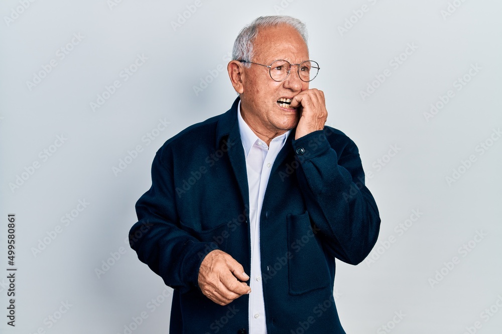 Senior man with grey hair wearing casual style and glasses looking stressed and nervous with hands on mouth biting nails. anxiety problem. Senior man with grey hair wearing casual style and glasses looking stressed and nervous with hands on mouth biting nails. anxiety problem.
