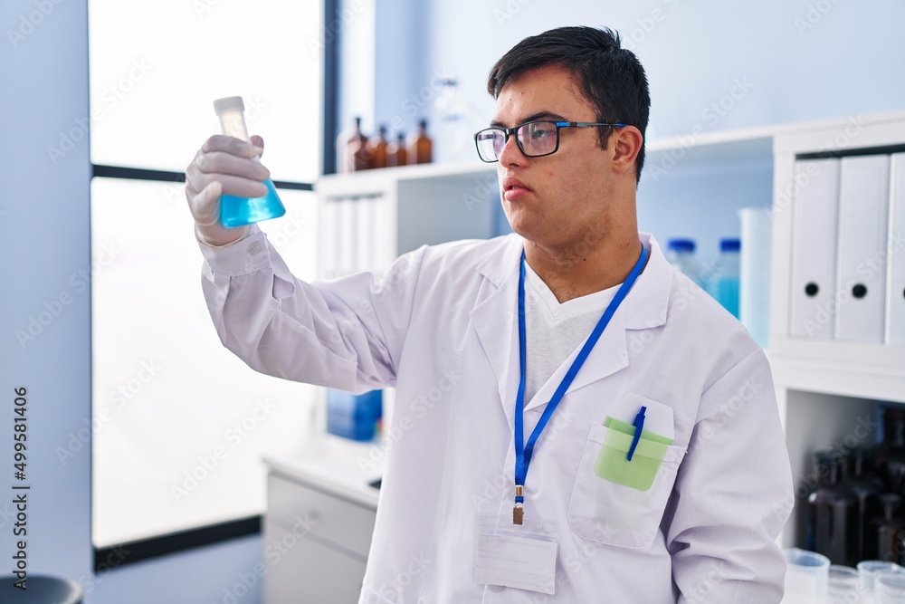 Down syndrome man wearing scientist uniform holding test tube at laboratory Down syndrome man wearing scientist uniform holding test tube at laboratory