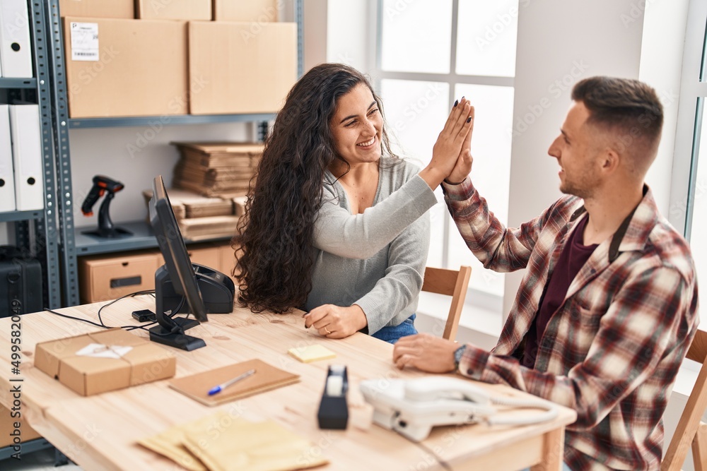 Man and woman ecommerce bussines workers high five with hands raised up at office Man and woman ecommerce bussines workers high five with hands raised up at office