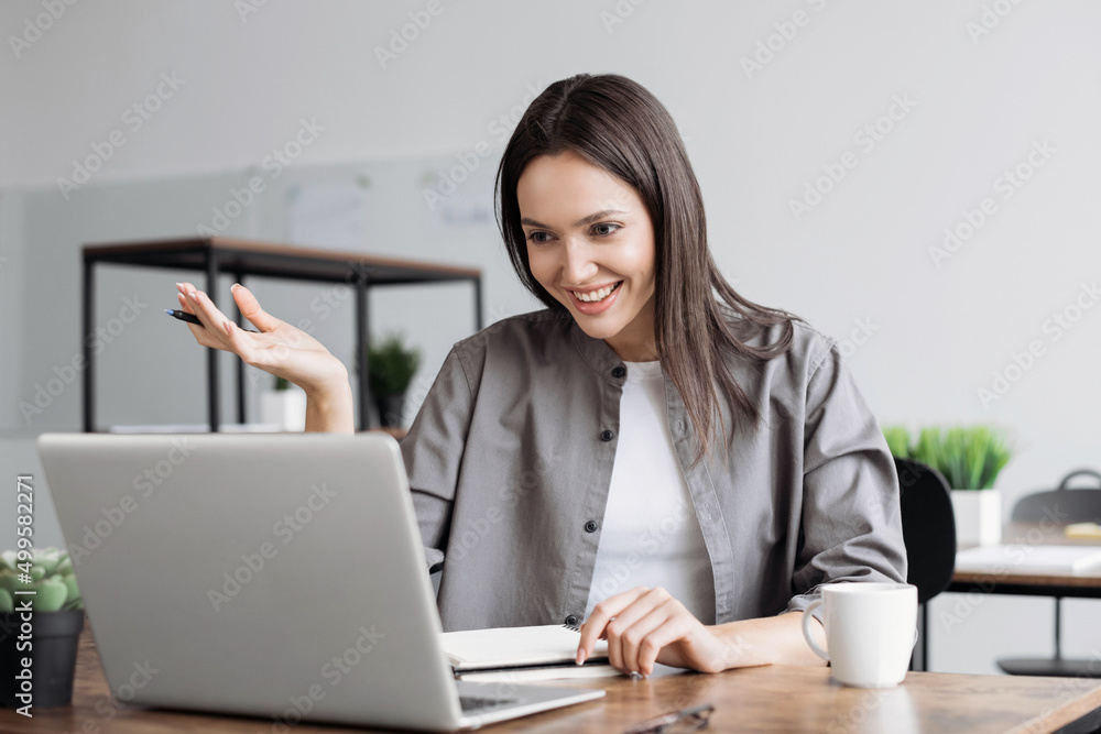 Beautiful business woman looking and speaking through the web camera while making a video conference from office, teacher working online Beautiful business woman looking and speaking through the web camera while making a video conference from office, teacher working online